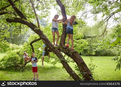 friendship, childhood, leisure and people concept - group of happy kids or friends climbing up tree and having fun in summer park. happy kids climbing up tree in summer park