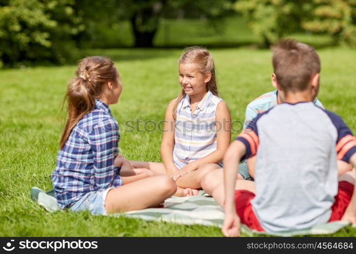 friendship, childhood, leisure and people concept - group of happy kids or friends sitting on grass in summer park