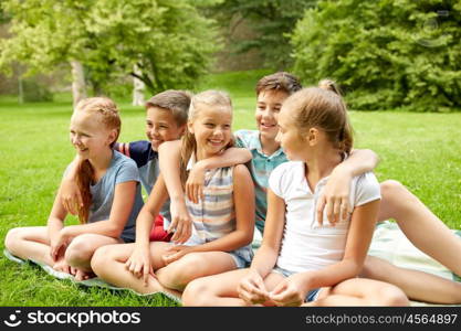 friendship, childhood, leisure and people concept - group of happy kids or friends sitting on grass in summer park