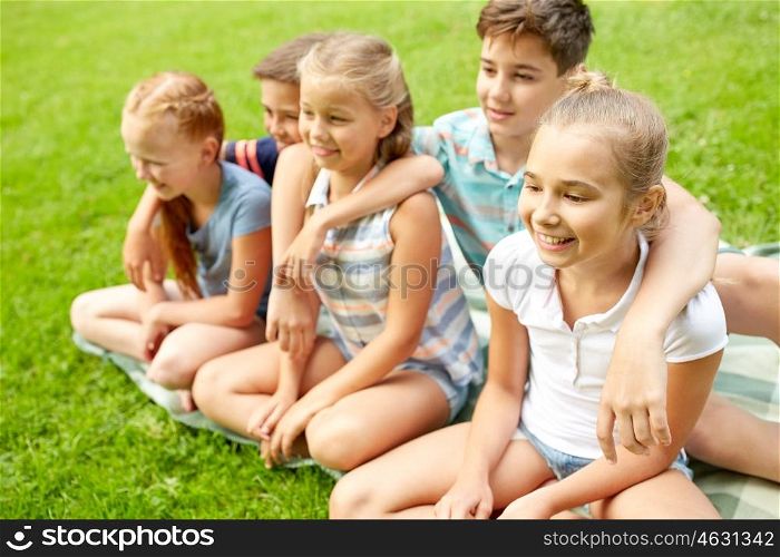 friendship, childhood, leisure and people concept - group of happy kids or friends sitting on grass in summer park
