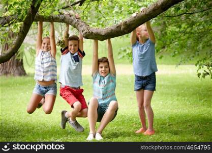 friendship, childhood, leisure and people concept - group of happy kids or friends hanging on tree and having fun in summer park
