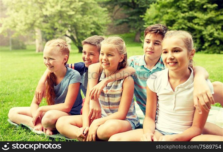 friendship, childhood, leisure and people concept - group of happy kids or friends sitting on grass in summer park. group of happy kids or friends outdoors