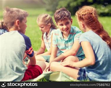 friendship, childhood, leisure and people concept - group of happy kids or friends sitting on grass in summer park. group of happy kids or friends outdoors