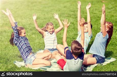 friendship, childhood, leisure and people concept - group of happy kids or friends sitting and having fun on grass in summer park. group of happy kids or friends outdoors