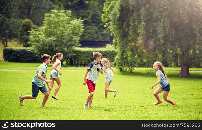 friendship, childhood, leisure and people concept - group of happy kids or friends playing catch-up game and running in summer park. happy kids running and playing game outdoors