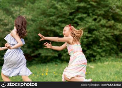 friendship, childhood, leisure and people concept - happy girls or friends playing tag game at birthday party in summer park. happy girls playing tag game at birthday party. happy girls playing tag game at birthday party