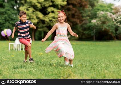 friendship, childhood, leisure and people concept - happy kids or friends playing tag game at birthday party in summer park. happy kids playing tag game at birthday party. happy kids playing tag game at birthday party