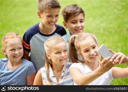 friendship, childhood, technology and people concept - group of happy kids or friends taking selfie by smartphone in summer park