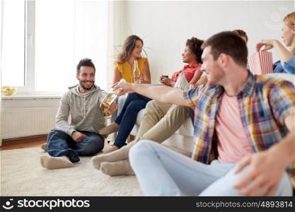 friendship, communication and people concept - group of happy friends with drinks talking at home