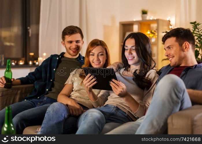 friendship, communication and people concept - group of happy friends with tablet computer drinking beer at home at night. friends with tablet computer drinking beer at home