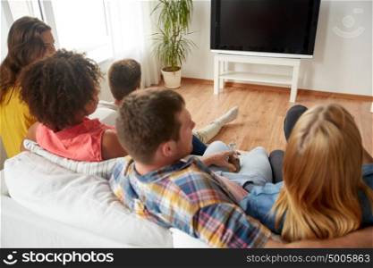 friendship, communication, people and entertainment concept - happy friends drinking beer or cider and watching tv at home. friends with beer watching tv at home