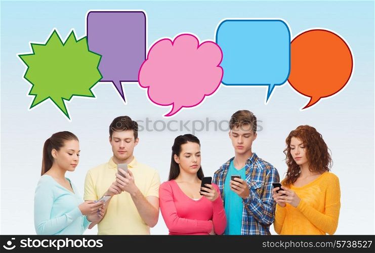 friendship, communication, technology and people concept - smiling friends showing blank smartphones screens over blue background with doodles
