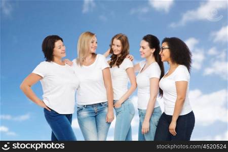 friendship, diverse, body positive and people concept - group of happy different size women in white t-shirts hugging over blue sky and clouds background