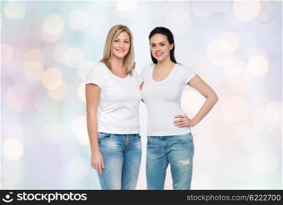 friendship, diverse, body positive and people concept - group of happy different women in white t-shirts hugging over holidays lights background