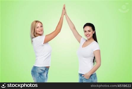 friendship, diverse, body positive, gesture and people concept - group of happy different women in white t-shirts making high five over green natural background