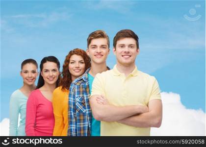 friendship, dream and people concept - group of smiling teenagers standing over blue sky with white cloud background
