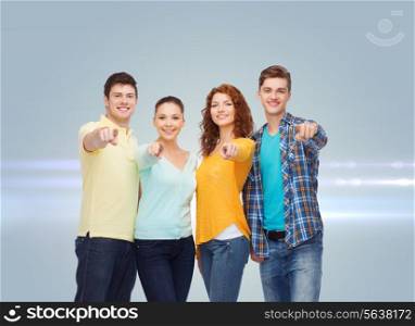 friendship, dream, future and people concept - group of smiling teenagers pointing fingers on you over gray background with laser light