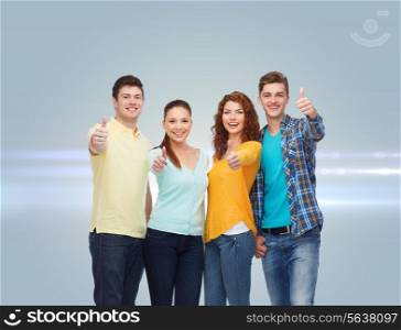 friendship, dream, future and people concept - group of smiling teenagers showing thumbs up over gray background with laser light