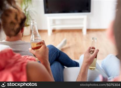 friendship, drink, alcohol, holidays and people concept - happy friends drinking beer and watching tv at home. friends drinking beer and watching tv at home