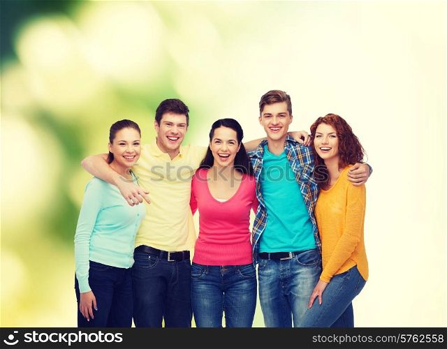 friendship, ecology and people concept - group of smiling teenagers standing and hugging over green background