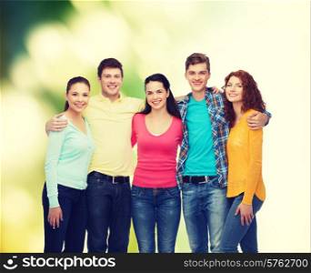 friendship, ecology and people concept - group of smiling teenagers standing and hugging over green background