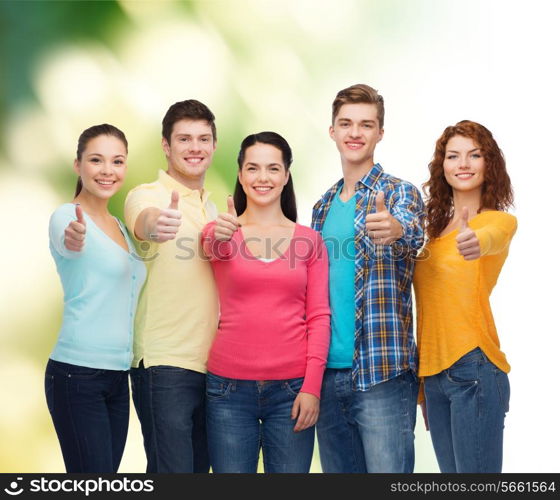 friendship, ecology, gesture and people concept - group of smiling teenagers showing thumbs up over green background