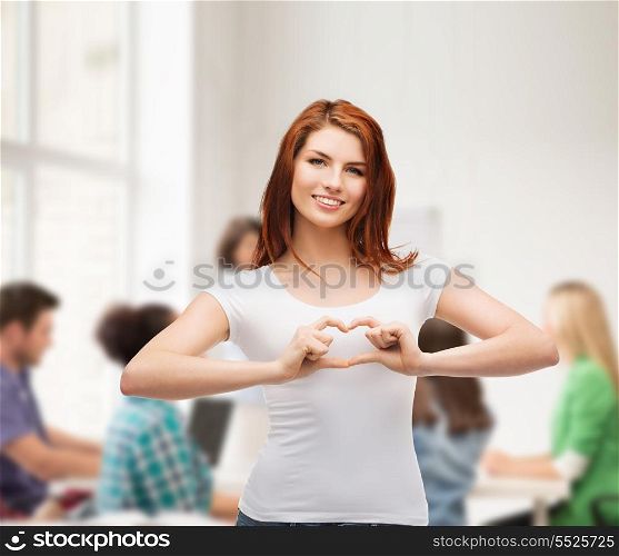 friendship, education and happy people concept - smiling girl in white t-shirt showing heart with hands