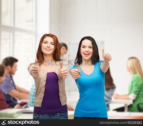 friendship, education and happy people concept - two smiling girls showing thumbs up