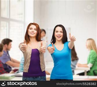 friendship, education and happy people concept - two smiling girls showing thumbs up