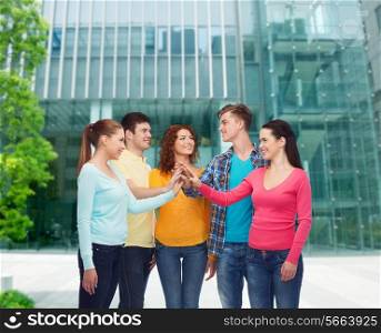 friendship, education, business, gesture and people concept - group of smiling teenagers making high five over campus background