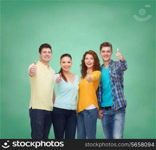 friendship, education, school and people concept - group of smiling teenagers showing thumbs up over green board background
