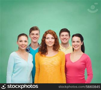friendship, education, school and people concept - group of smiling teenagers standing over green board background