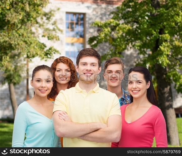 friendship, education, summer vacation and people concept - group of smiling teenagers standing over campus background