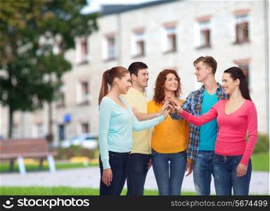 friendship, education, teamwork, gesture and people concept - group of smiling teenagers making high five over campus background