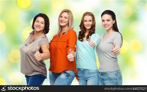 friendship, fashion, body positive, gesture and people concept - group of happy different size women in casual clothes showing thumbs up over green holidays lights background