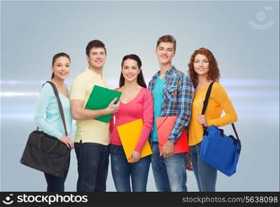 friendship, future, education and people concept - group of smiling teenagers with folders and school bags over gray background with laser light