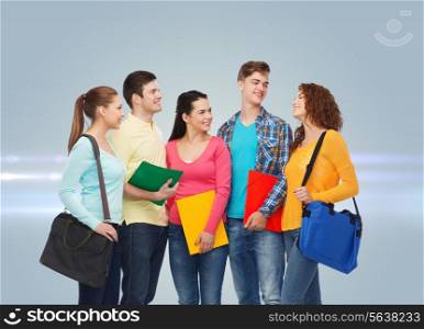 friendship, future, education and people concept - group of smiling teenagers with folders and school bags over gray background with laser light