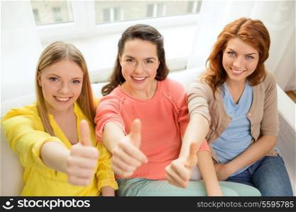 friendship, gesture and happiness concept - three girlfriends showing thumbs up at home