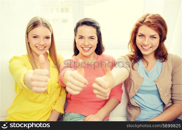 friendship, gesture and happiness concept - three girlfriends showing thumbs up at home