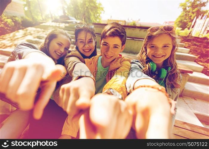 friendship, gesture and people concept - happy teenage friends or high school students pointing finger at you. teenage friends or students pointing finger at you