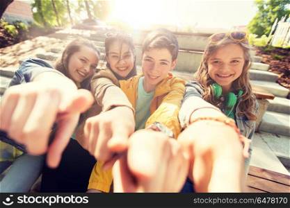 friendship, gesture and people concept - happy teenage friends or high school students pointing finger at you. teenage friends or students pointing finger at you. teenage friends or students pointing finger at you