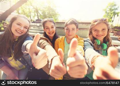 friendship, gesture and people concept - happy teenage friends or high school students showing thumbs up. teenage friends or students showing thumbs up. teenage friends or students showing thumbs up