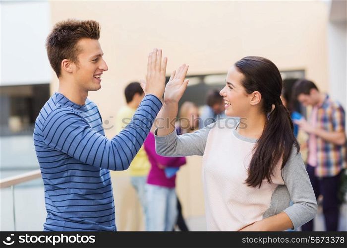 friendship, gesture, education and people concept - group of smiling students outdoors making high five