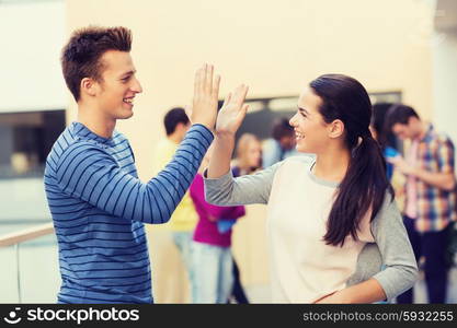 friendship, gesture, education and people concept - group of smiling students outdoors making high five