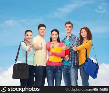 friendship, gesture, education and people concept - group of smiling teenagers with folders and school bags showing thumbs up over blue sky with white cloud background