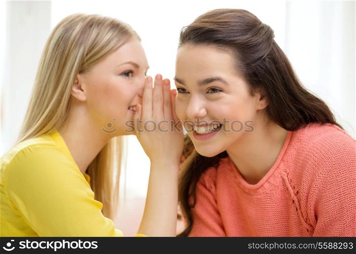 friendship, gossip and happiness concept - one girl telling another secret