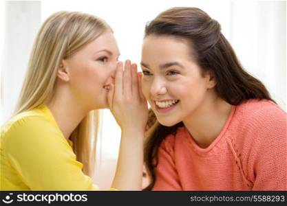 friendship, gossip and happiness concept - one girl telling another secret