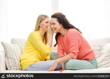 friendship, gossip and happiness concept - one girl telling another secret