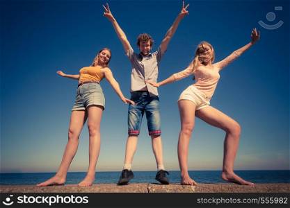 Friendship happiness summer holidays concept. Group of friends boy two girls having fun outdoor stretching arms celebrating, wide angle view. Group friends boy two girls having fun outdoor