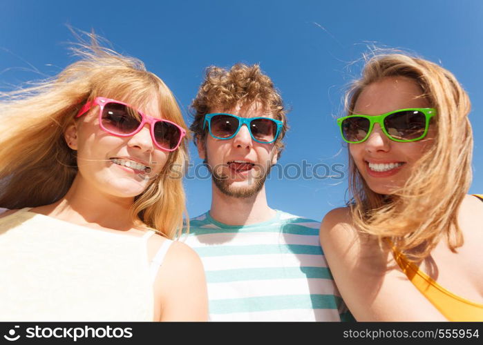 Friendship happiness summer holidays concept. Group of friends boy two girls in colorful sunglasses having fun outdoor against sky, joy playful mood.. Group friends boy two girls having fun outdoor